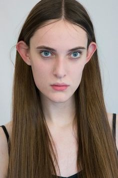 a woman with long brown hair and blue eyes is looking at the camera while wearing a black top