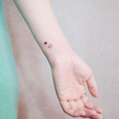 a small star tattoo on the left inner wrist is shown in black ink, and it appears to be tiny