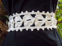 a white crocheted belt with hearts and flowers on the side, attached to a black shirt