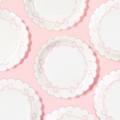 many white plates are arranged on a pink background with scalloped edges and circles