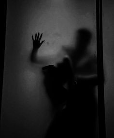 the shadow of a person reaching out from behind a wall with their hands in the air