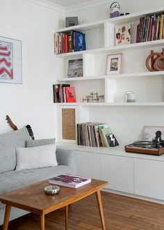 a living room filled with furniture and bookshelves next to a wooden coffee table