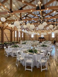 the inside of a large barn with tables and chairs set up for a formal function