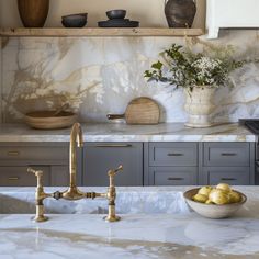 a kitchen with marble counter tops and gold faucets