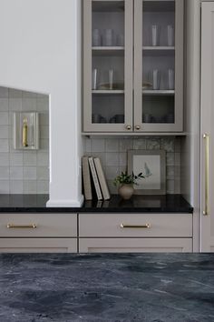 a kitchen with white cabinets and black counter tops, gold pulls on the door knobs