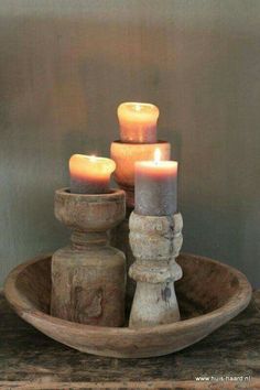 three lit candles sit in a wooden bowl