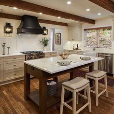 a large kitchen with an island in the middle and two stools at the end