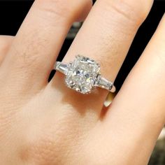 a woman's hand with an engagement ring on top of her finger, showing the center stone