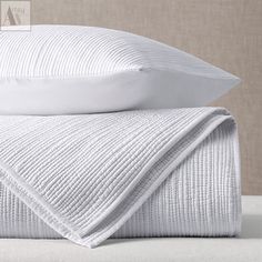 two white pillows stacked on top of each other next to an unmade pillow case