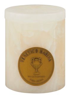 a white candle with a gold label on it