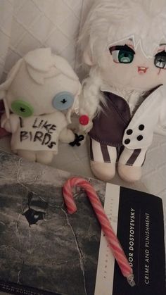 two stuffed animals sitting next to each other on a bed with a candy cane in front of them