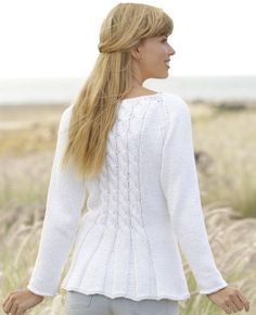 a woman with long blonde hair wearing a white sweater and jeans standing in tall grass