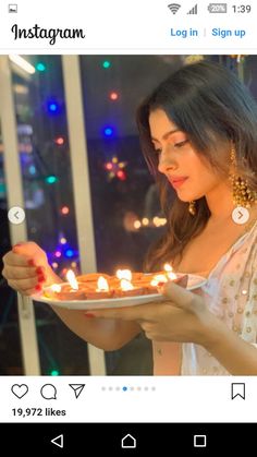 a woman holding a plate with lit candles on it