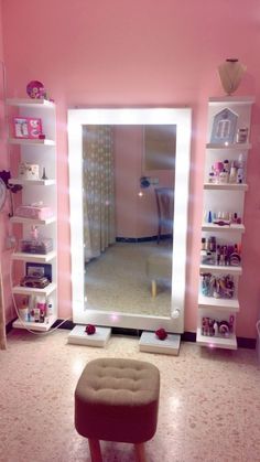 a mirror sitting on top of a pink wall next to a footstool in a room