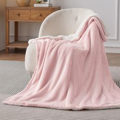 a pink blanket sitting on top of a white chair