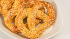 sesame seed pretzels in a white bowl on a white tablecloth, ready to be eaten