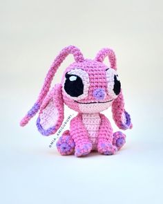 a pink and purple crocheted stuffed animal sitting on top of a white surface