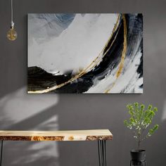 a painting hanging on the wall next to a table and vase with a plant in it