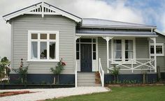 a grey house with white trim on the front and side windows, grass in front