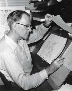 a man sitting at a desk with papers in front of him and an open book