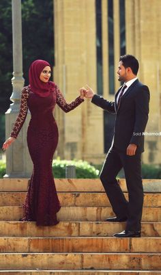 a man and woman standing on steps holding hands