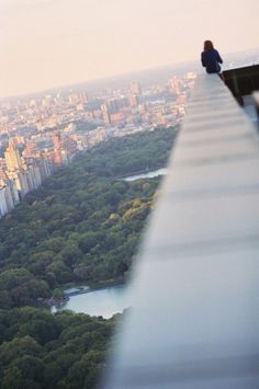 a person sitting on the edge of a building looking out over a cityscape