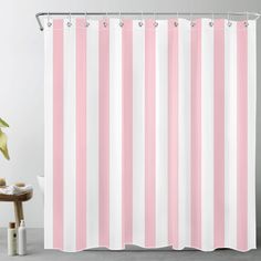 a pink and white striped shower curtain next to a table with a potted plant