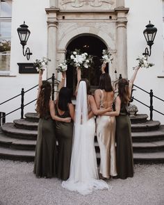 four bridesmaids are sitting on the steps with their arms in the air as they look at each other