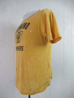 "Vintage 1960s yellow cotton t shirt with black graphics: Richmond Brewers Little League Baseball. Made by Southern Athletic. Size small. Actual measurements are: 38\" around the chest 38\" around the waist 17.5\" shoulder seam to shoulder seam 23\" overall length In \"wrecked\" condition with several holes." Vintage Fitted T-shirt With Letter Print, Fitted Yellow T-shirt With Screen Print, Mustard Graphic Print Cotton T-shirt, Mustard Cotton T-shirt With Graphic Print, Retro Yellow T-shirt With Graphic Print, Retro Yellow T-shirt With Screen Print, Vintage Cotton T-shirt With Screen Print, Vintage Yellow Tops With Screen Print, Vintage Yellow Top With Screen Print