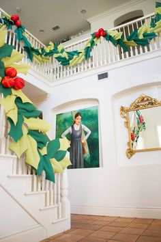 a staircase decorated with christmas decorations and greenery in front of a painting on the wall