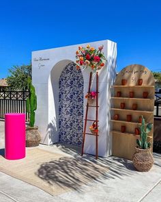 a white building with blue and pink decorations on the outside, including a ladder that has flowers in it