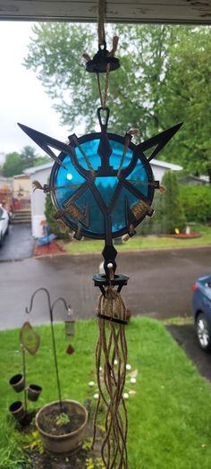 a wind chime sitting on top of a lush green grass covered field next to a blue car