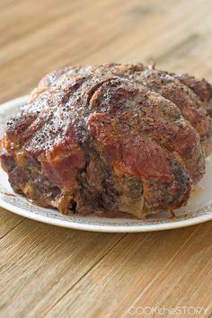 a piece of meat sitting on top of a white plate next to a wooden table