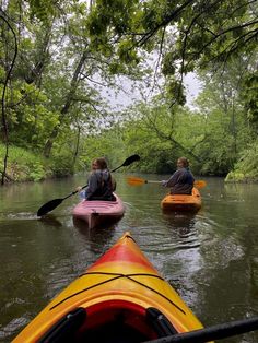 two people in kayaks paddling down a river