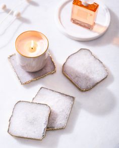 three coasters on a table with a candle in the middle and some other items around them