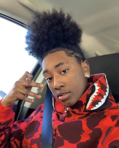 a young man sitting in the back seat of a car with an afro on his head