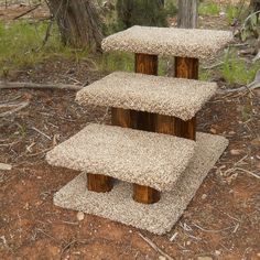 three tiered wooden stand made out of wood logs in the dirt near trees and grass