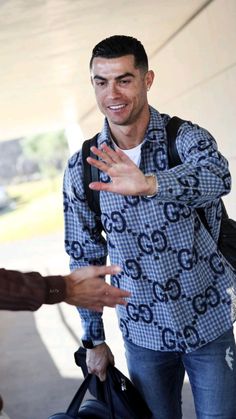 a man with his hand out to another person who is holding a bag and smiling