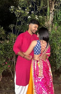 a man and woman standing next to each other in front of some trees at night