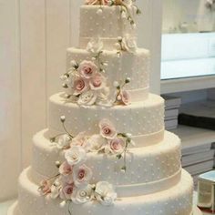 a three tiered wedding cake with pink flowers on the top and white polka dots