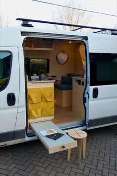 a white van with its door open and some tables in front of it on a brick walkway