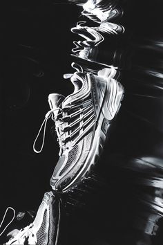 black and white photograph of running shoes in the water, with reflections on the ground