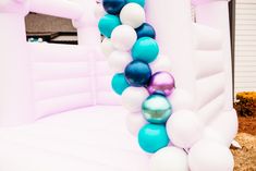 an inflatable arch decorated with blue, white and pink balloons