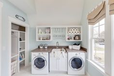 a washer and dryer in a small room with open shelves on the wall