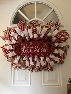 a red and white wreath that says let it snow on the front door with ribbon