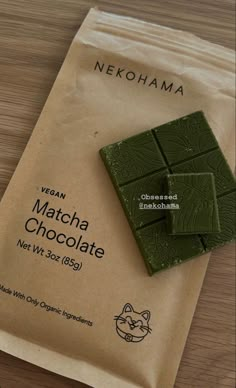 a bag of vegan matcha chocolate sitting on top of a wooden table next to a packet of catnip