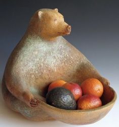 a ceramic bear sitting in a bowl filled with fruit