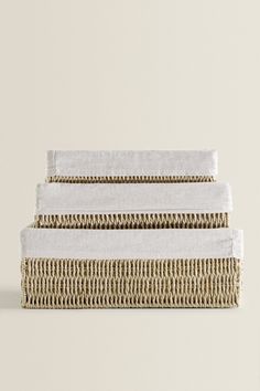 three white towels stacked on top of each other in front of a beige wall and floor