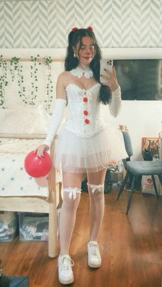 a woman in a white corset holding a red ballon while standing next to a bed