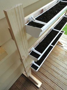 a wooden deck with black seed trays attached to the sides and white rails on each side